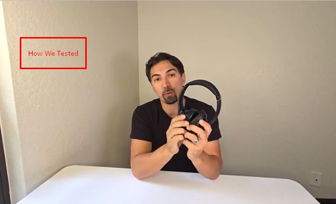 Man holding Soundcore Q20i headphones in both hands while testing them at a table