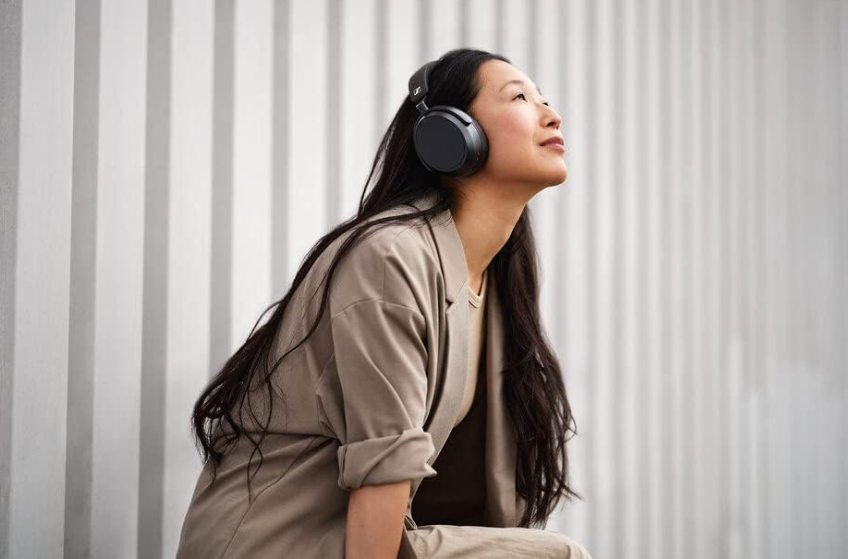 Woman wearing black Sennheiser Momentum 4 over-ear headphones