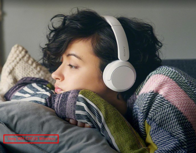 Person wearing white Sony WH-CH520 wireless on-ear headphones while resting on a pillow
