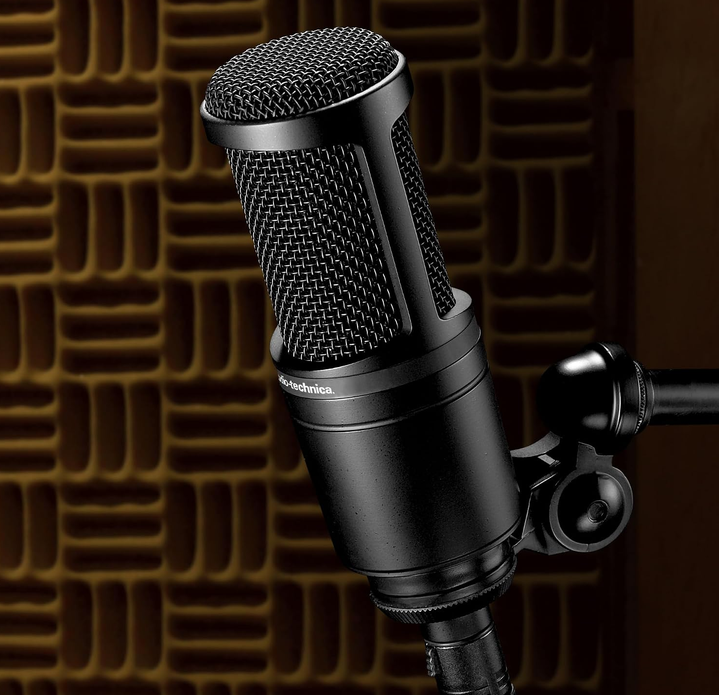 Close-up of the Audio-Technica AT2020 condenser microphone on a stand in front of acoustic foam panels